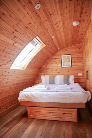 Ein gemütliches Schlafzimmer mit Holzwänden, einem Einzelbett, einem Dachfenster und einer gerahmten Karte an der Wand.