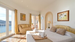 Een ruime slaapkamer met een groot bed, een sofa en uitzicht op zee.