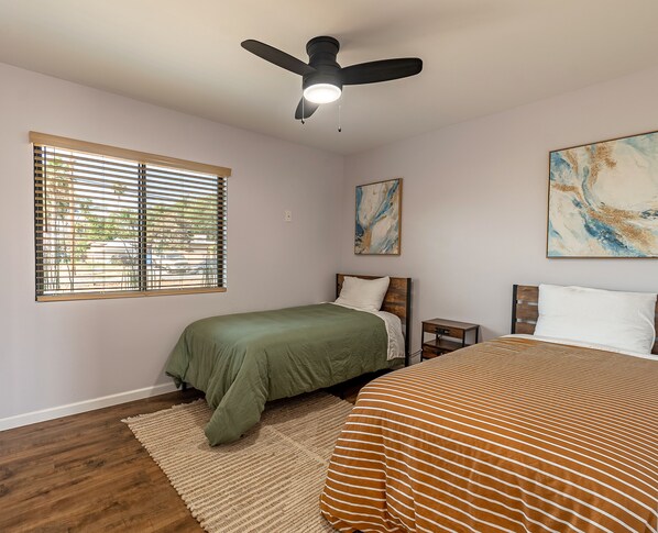 A bedroom with two beds, a ceiling fan, a window with blinds, and artwork on the walls. - Sunny Escape with Pool near colleges, park, shopping, restaurants, convention (Riverside)