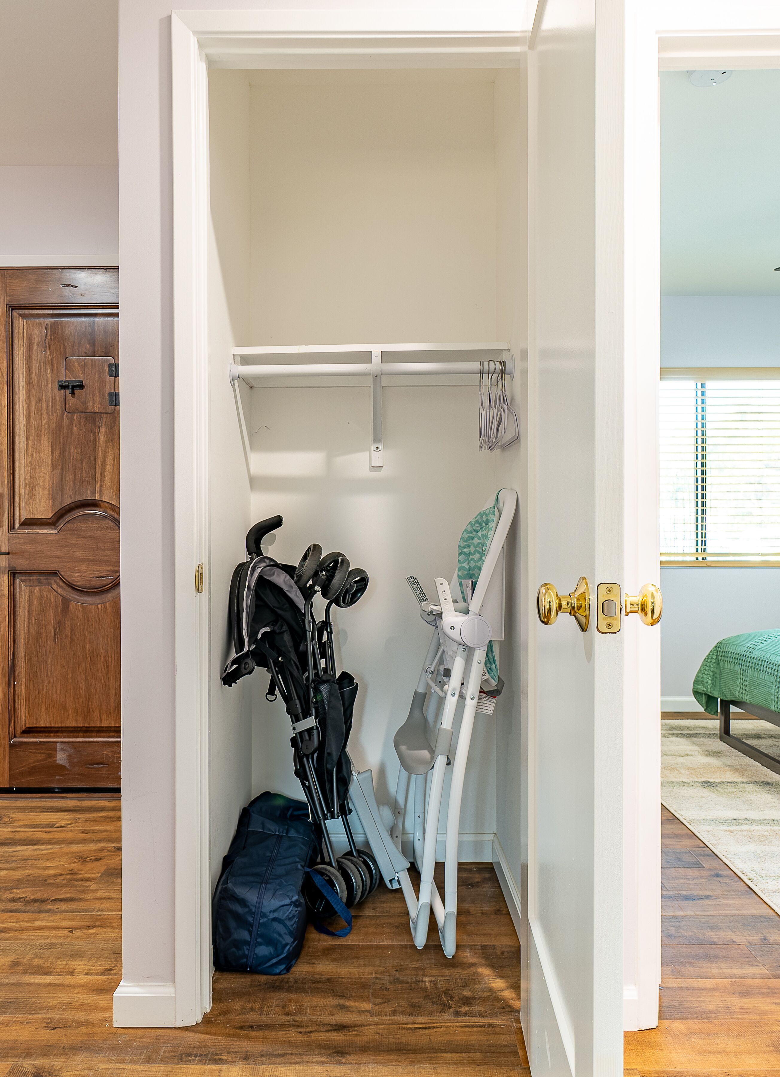 A compact room with a wooden door, a white wall, and a small window.