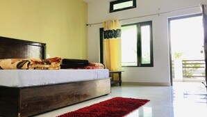 A bedroom with a bed, a red rug, a window with curtains, and a balcony. - Hotel The Himalaya Orchid Guptkashi (Ukhimath)