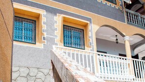 A staircase leading to a building with a stone wall and a balcony with a railing.