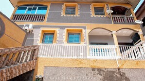 A multi-story building with balconies, a covered porch, and a staircase.