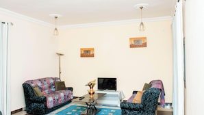 A living room with two sofas, a coffee table, a TV, and two wall-mounted paintings.