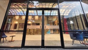 A hotel entrance with a glass facade, a central reception desk, and a view of the interior through the glass. - Luxurious Suites in Kl Centre (Kuala Lumpur)