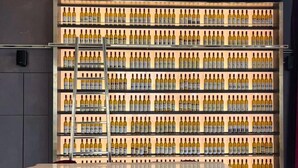 A bar area with a wall of wine bottles, a white counter, and three red bar stools. - Luxurious Suites in Kl Centre (Kuala Lumpur)