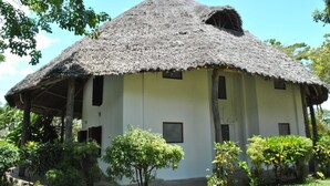 Una casa de techo de paja con una estructura sencilla de un solo piso y un pequeño porche.