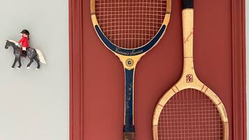 Dos raquetas de tenis y una figurita sobre una superficie roja.