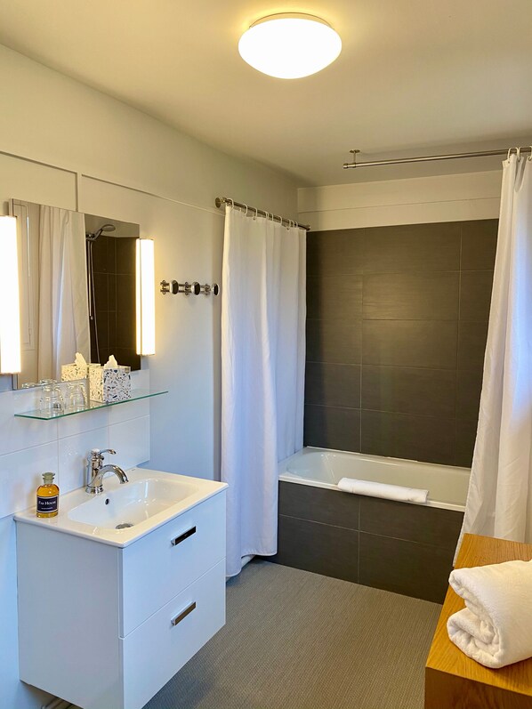 Un baño moderno con un tocador blanco, una bañera y una zona de ducha.