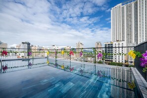 Ein Pool auf dem Dach mit Glasumrandung und bunten Blumen.