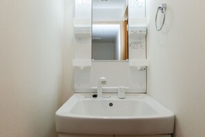 A white bathroom sink with a mirror above it, a towel rack on the wall, and a door leading to another room.