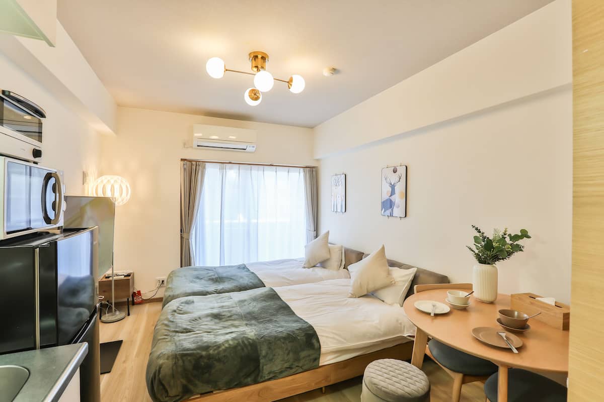 Une chambre d’hôtel moderne comprenant un lit, une table de chevet et un coin repas avec une table et des chaises.