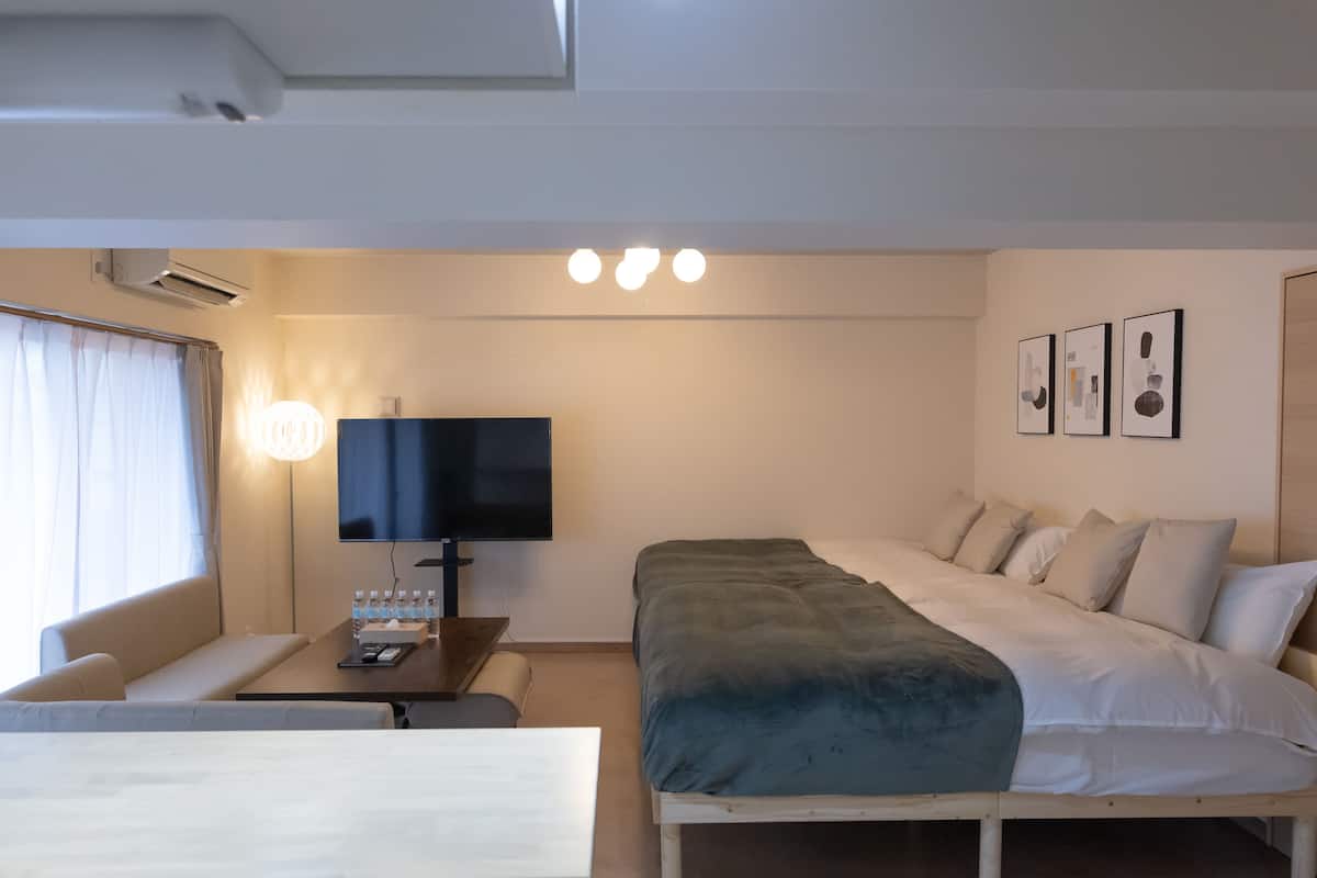 Une chambre d’hôtel avec un lit, une télévision, une table de chevet et une fenêtre avec des rideaux.