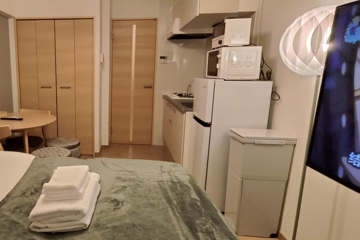 Une chambre d’hôtel comprenant un lit, une petite table ronde avec une chaise, un coin cuisine et un téléviseur.