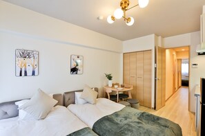A modern hotel room with a bed, bedside table, and a small dining area.