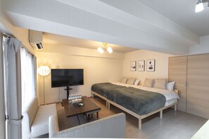 Una habitación de hotel moderna con una cama, un televisor, un escritorio y un sofá.