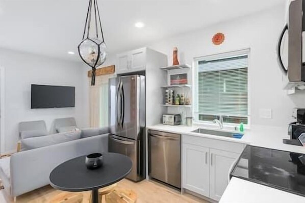 Una cocina compacta con refrigerador, lavavajillas y un pequeño comedor con mesa y sillas.