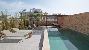 Ein Pool auf dem Dach mit Liegestühlen, einem Tisch und einer Pergola.