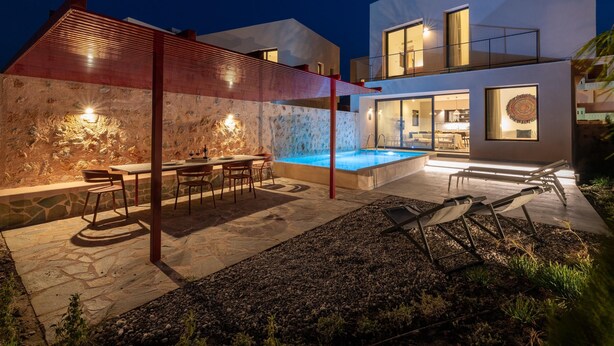 Ein modernes Haus mit Swimmingpool, Sitzgelegenheit im Freien und einer Steinmauer.
