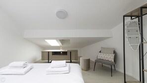 A modern bedroom with a lofted sleeping area, a small desk, a chair, and a hanging laundry rack. - Italianway Easy - Settala 51 (Milan)
