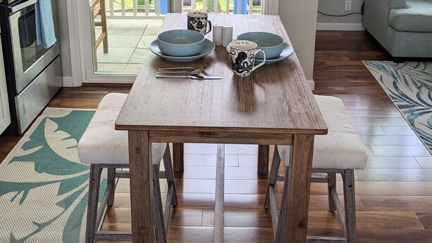 A dining area with a wooden table, blue plates, and a decorative mug. - Light and breezy Kailua apartment (Kailua)