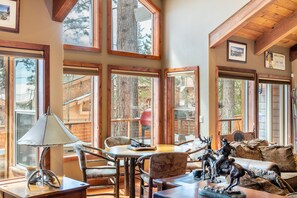 A cozy interior with large windows, wooden furniture, and a welcome sign.