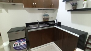 A compact kitchen with a sink, a coffee maker, and a small cabinet.