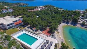 Oversigtsbillede af et kystområde med swimmingpool, strand og omkringliggende bygninger.