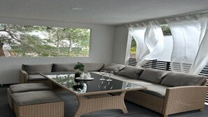 Et moderne udendørs opholdsområde med sofa, skammel og bord med glasplade.