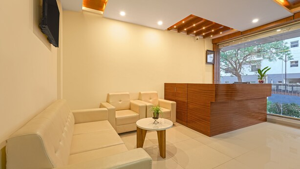 Un área de recepción moderna con un sofá, una mesita redonda con una planta y un mostrador de madera.