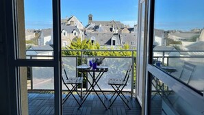Un balcon avec une table et des chaises, donnant sur une ville où se trouvent des bâtiments historiques.