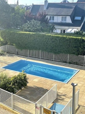 A rectangular swimming pool with a tiled deck, surrounded by a white metal fence. - Plage, Piscine, Terrasse & Centre-ville à Quiberon (Quiberon)
