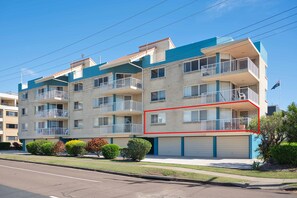 A multi-story residential building with balconies, a garage, and a clear sky.