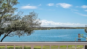 A lake with a tree and a sign in the foreground.