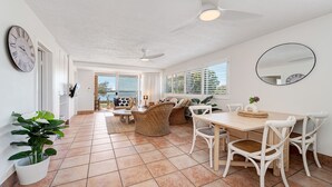 A spacious living area with a dining table, chairs, and a ceiling fan. - Unit 1 Seascapes Golden Beach Waterfront Balcony (Golden Beach)