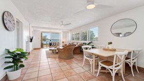 A spacious living area with a dining table, chairs, and a ceiling fan.