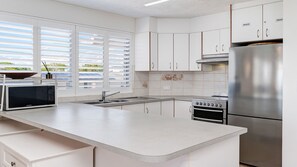 Una cucina moderna con mobili bianchi, un frigorifero in acciaio inossidabile, forno integrato e microonde.