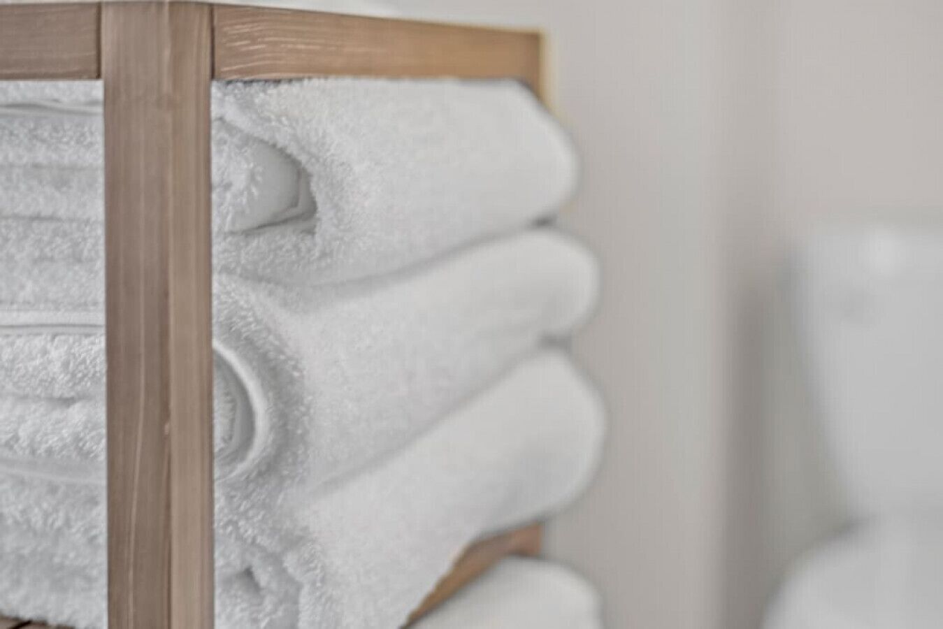 A stack of white towels on a wooden rack.
