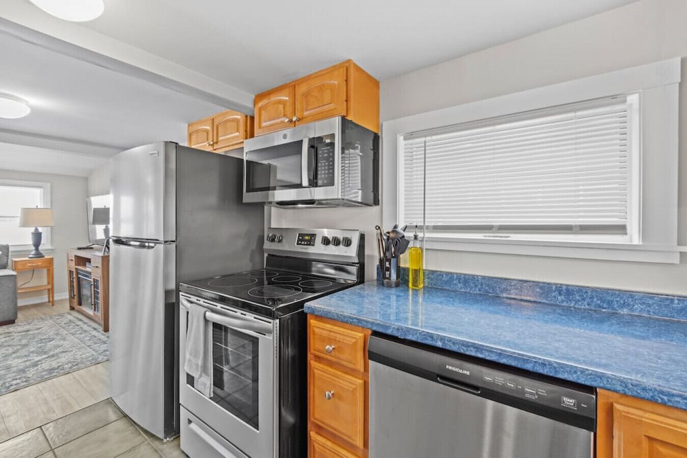 A modern kitchen with stainless steel appliances, wooden cabinets, and a blue granite countertop.