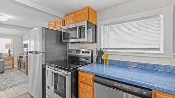 A modern kitchen with stainless steel appliances, wooden cabinets, and a blue granite countertop.