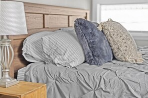 A bed with a grey duvet, a wooden headboard, and three pillows. - Colchester Lake Getaway! (Colchester)