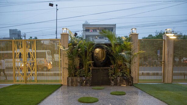 A gated entrance with a central decorative element, flanked by two gates, leading to a building with a modern facade. - Dev Royale Hotel (Gurugram)