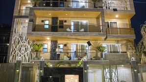 A multi-story hotel with a modern facade, balconies, and a well-lit entrance. - Dev Royale Hotel (Gurugram)