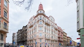 A multi-story building with a pink facade and a red roof, featuring balconies and large windows. - Beautiful Mala Strana Studio by EasyBNB Premium (Prague)
