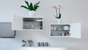 A modern kitchen with white cabinetry, a coffee maker, a kettle, and a sink. - Beautiful Mala Strana Studio by EasyBNB Premium (Prague)