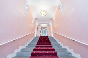Eine prächtige Treppe mit rotem Teppich, weißen Geländern und einem Chandelier an der Spitze.