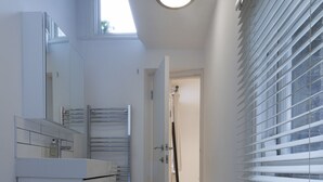 A modern bathroom with a white vanity, a towel rack, and a shower area. - Large flat near Oxford Circus (London)
