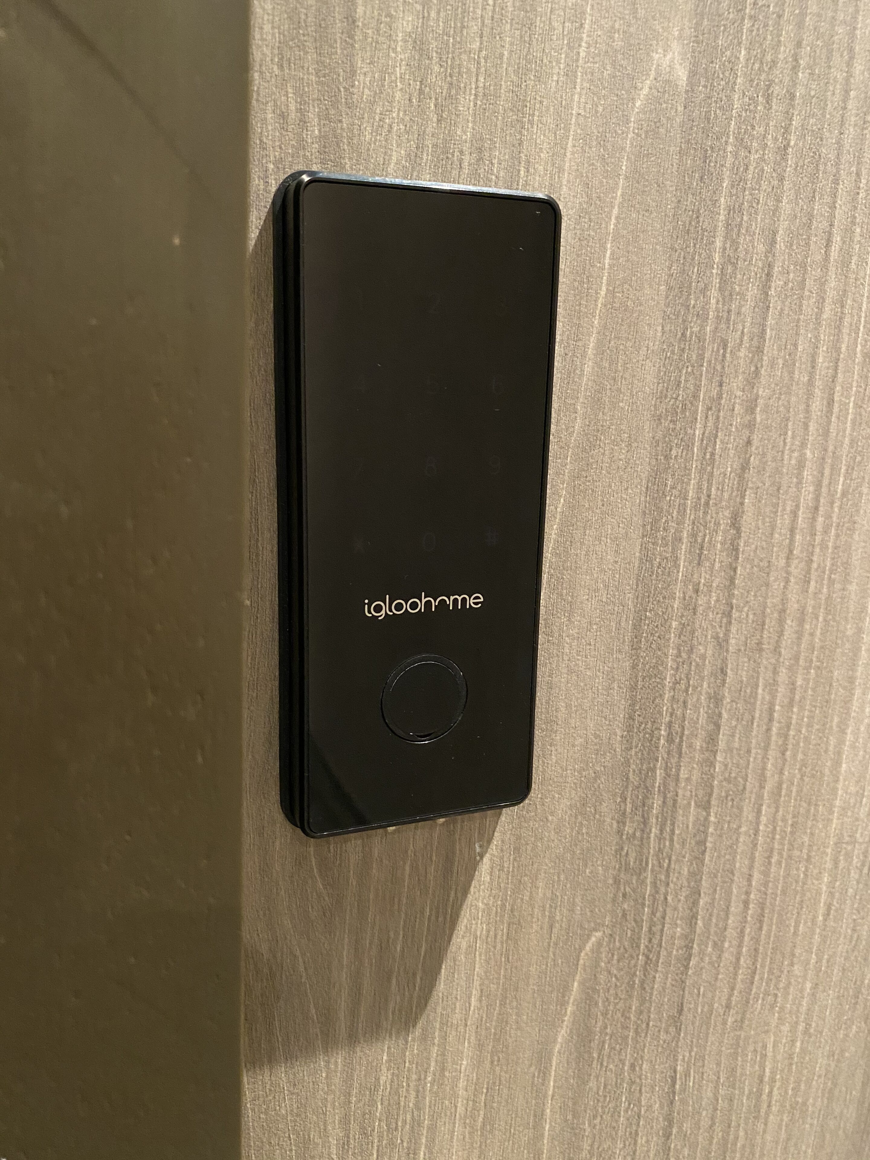 Un dispositivo electrónico negro con el nombre de marca 'igloohome' sobre una superficie de madera.