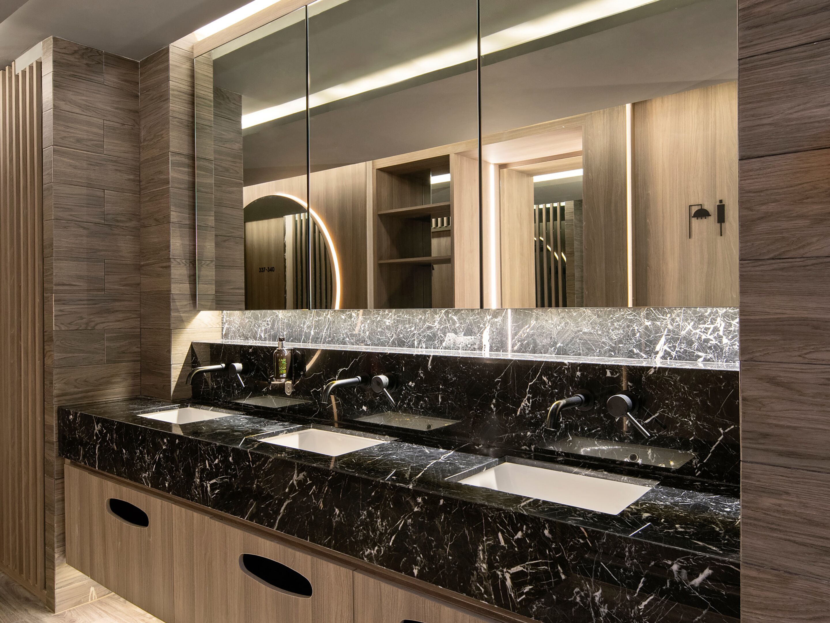 Un baño moderno con encimera de mármol negro, dos lavabos y un espejo grande.