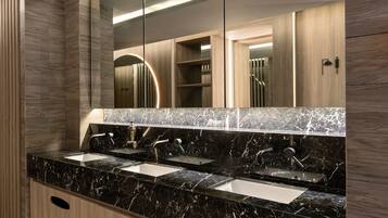 Un baño moderno con encimera de mármol negro, dos lavabos y un espejo grande.